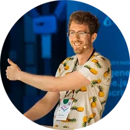 Josh smiling and giving a thumbs up at a podium wearing a white shirt with a pineapple pattern